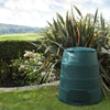 Image of Green Johanna compost bin in a garden setting with plants and a clear sky.