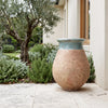 Image of Celadon glazed French Biot jar with antiqued terracotta base on a paved patio