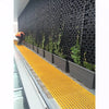 Image of man installing pots at the bottom of an atlantis facade wall, with climbing plants growing up the trellis