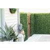 Image of An image of a side yard with the Artificial Flowering Buxus Hedge Plant Panels installed around the rustic wooden gate, white-sided house with wall disc planter, potted greenery, and a clean white paver walkway
