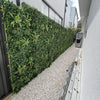 Image of Artificial Green Meadows 1m x 1m Plant Wall Panel UV Stabilised installed in a residential backyard along a pebble stone pathway with a ladder positioned in front
