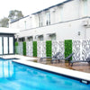 Image of Image of an outdoor pool area with a wooden deck, dark lounge chairs, and a decorative fence alternating black and white patterned panels and Artificial Lavandula Vertical Garden Plant Wall Screening Panels