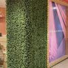 Image of Artificial Premium Natural Buxus Panel mounted on a surrounding wall inside a mall, positioned next to a poster
