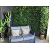 Image of Artificial Red Tropics Vertical Garden Panel Installed on patio with small outdoor couch in the foreground