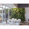 Image of Modern interior with white tables and chairs against a green living wall.