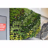 Image of Green living wall with plants in an indoor setting, featuring a staircase and a fire exit sign.