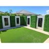 Image of An image of a backyard with patterned walls of alternating Artificial Deluxe Buxus Hedge Wall Panels and laser cut black panels, bright green turf, light pavers and a home roof under a clear sky