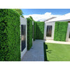Image of A photo of a backyard walkway with light pavers, patterned walls of Artificial Deluxe Buxus Hedge Wall Panels and laser-cut black panels and bright green turf under strong sunlight