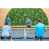 Image of Evergreen Rainforest Recycled Artificial Green Wall Panel framed by wood toned wall paneling with four men actively playing a doubles match of pickleball