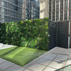 Image of Evergreen Rainforest Recycled Artificial Green Wall Panel installed outside the gate of a commercial building with grass on the ground