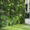 Image of Evergreen Rainforest Recycled Artificial Green Wall Panel installed on a wall beside a gate with grass on the ground