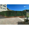 Image of A freestanding privacy wall with wood look posts and Artificial Jasmine Hedge Plant Wall Screen Panels, situated on a stone patio against a modern building and grassy hillside under a clear blue sky