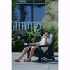 Image of Man relaxing on a modern graphite adirondack chair with a garden and house in the background