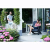 Image of Two people sitting on a porch with flowers and plants around.