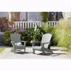 Image of Two gray Adirondack chairs on a patio with plants and flowers in the background.