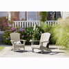 Image of Two Adirondack chairs on a patio with plants and flowers in the background.