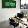 Image of Artificial White Oasis Vertical Garden Panel with LED letter lights mounted on an office wall complemented by a table, chair, computer, telephone, office supplies, potted plant, and a large window
