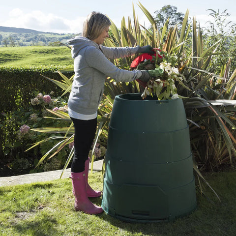 Person in garden with Green Johanna compost bin and plants
