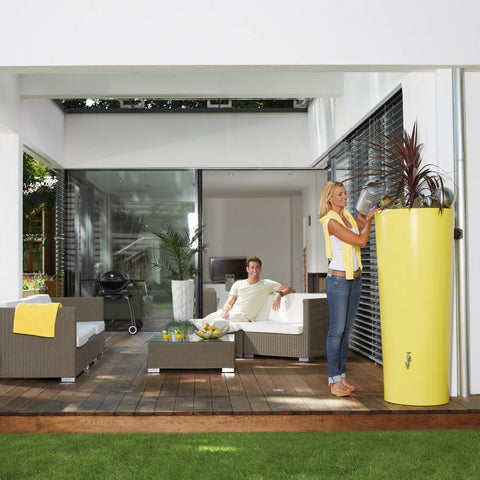 Modern outdoor living space with people sitting on a sofa and a yellow 350L Color 2in1 MiniTank planter.