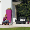 Image of Woman kneeling next to a 2in1 MiniTank planter with greenery on a patio.