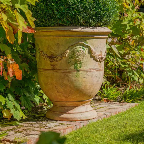 Decorative garden urn on a stone path with greenery
