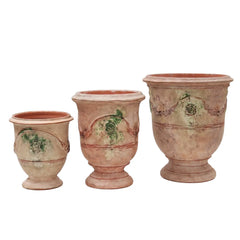 Three terracotta antique urns with decorative patterns on a white background