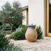 Image of blue glazed French Biot jar with antiqued terracotta base on paved entryway