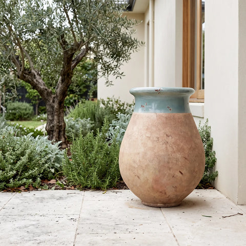 Celadon glazed French Biot jar with antiqued terracotta base on a paved patio
