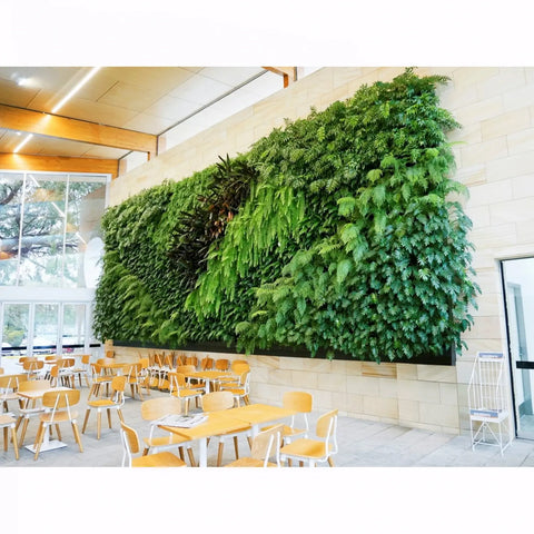 Green living wall in a modern indoor setting with tables and chairs.