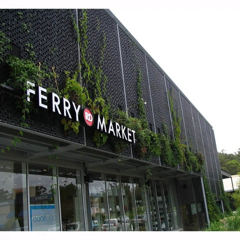 black facade panels installed above a market entrance with plants growing on it