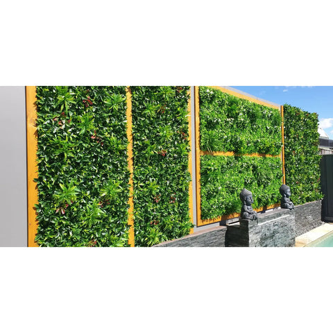 Artificial Green Meadows 1m x 1m Plant Wall Panel UV Stabilised installed on a concrete wall with wooden accents styled with figurines and displayed beside a swimming pool