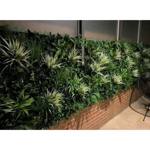 Artificial White Grass & Fern Vertical Garden installed on a glass wall above a brick base, beside a seating area