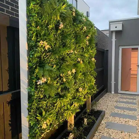 Artificial White Tropics Vertical Garden Wall Panel mounted on a concrete wall in a residential backyard featuring a stone paved ground beside the backdoor