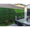 Image of A covered outdoor patio featuring floor to ceiling Artificial Deluxe Buxus Hedge Wall panels, a glass dining table, chairs and a turf strip with plants and a decorative statue