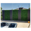 Image of A modern backyard patio with a patterned privacy fence of dark slats and Artificial Deluxe Buxus Hedge Wall Panel a hot tub on stone pavers and a clear sunny sky 
