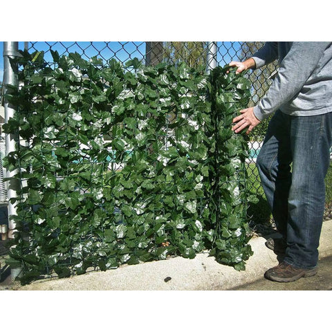 Image of a man installing the Double Sided Artificial Ivy Roll 3m x 1m Screen on a fence outdoors