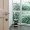 Image of A room corner featuring white plantation shutters. The partially open slats look out onto the Artificial Ivy Leaf Hedge 1m x 1m Plant Wall Screening Panel UV Protected installed on a wall outdoors