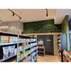 Image of Specialty store interior featuring the Artificial Ivy Leaf Hedge Panels above doors, bright track lighting, neatly stocked shelves, and a mix of concrete and textured walls