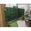 Image of Image of a modern backyard patio featuring a tall Artificial Ivy Leaf Hedge Panel that acts as a lush green privacy screen. The space is divided between a paved area with dining set and an adjacent patch of bright artificial grass