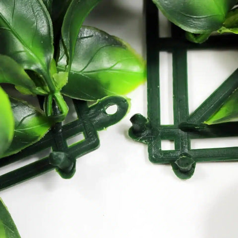 A close up of Artificial Jasmine Hedge panel showing the dark green grid backing and interlocking male and female connectors with leaves visible on top