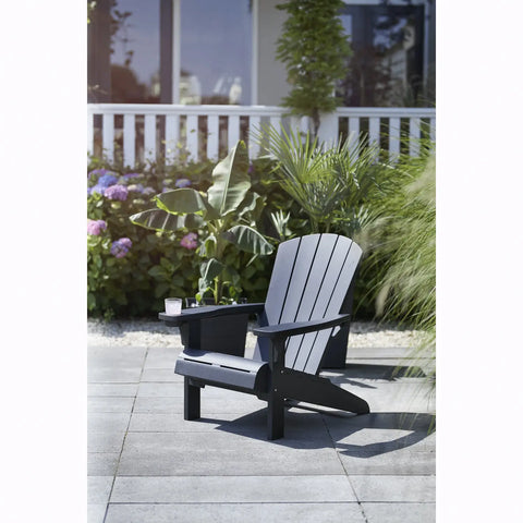 Graphite Adirondack chair on a patio with plants and flowers in the background