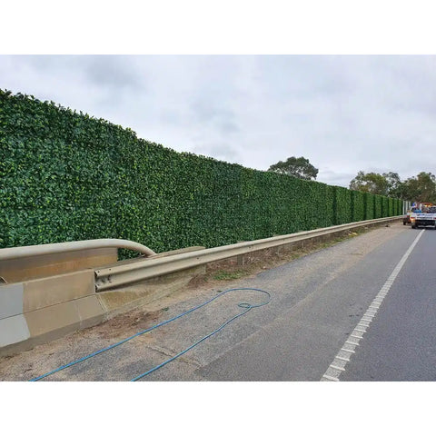 Artificial Laurel Hedge Panels installed alongside a highway acting as a visual and sound barrier behind a guardrail 