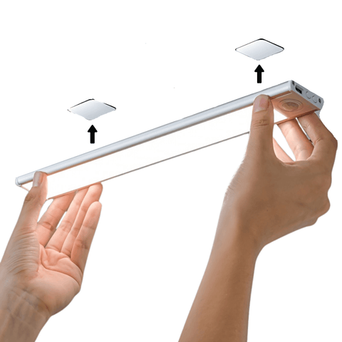 Hands holding an LED light strip with two magnets attached on a white background