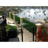 Image of Artificial Spring Sensation Hedge Wall Panels provide privacy on a terrace overlooking a bay with anchored boats, waterfront homes, lounge chairs, and potted flowers