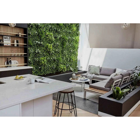 Artificial White Oasis Vertical Garden Panel mounted on a wall in an indoor setting positioned next to a decorative bottle rack. The room also features a countertop, chair, table, and a cozy sofa