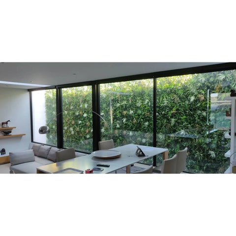Wild Tropics Artificial Vertical Garden Panel installed outdoors as a backdrop overlooking the glass windows of the living and dining area